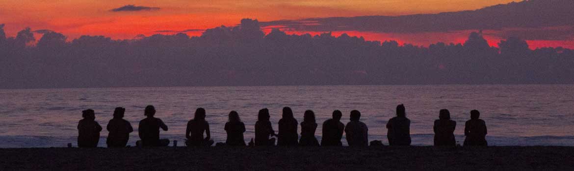 silhouette of people sitting watching a sunset